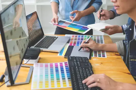 a team of people deciding color schemes at a table in front of computers